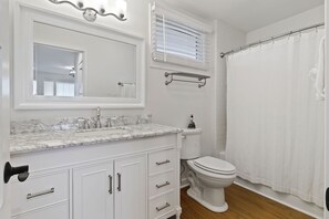 A bathroom with a white vanity, a sink with a marble countertop, a toilet, and a shower curtain. - Oceanfront Views, Community Pool, Great Resort Location! (Isle Of Palms)