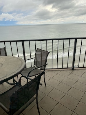 Enjoy the serene ocean views from this balcony with a round table and two chairs.