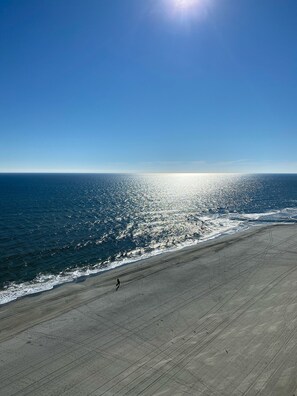 En strand med klar himmel och en sol som skiner på vattnet.