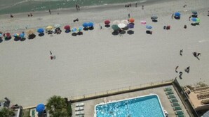 Luchtbeeld van een strand met een zwembad en ligstoelen.