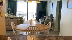 Een hotelkamer met een eethoek, een keuken met een spoelbak en een balkon met gordijnen.