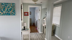 A hallway with a white console table, a lamp, and a red crab decoration. - One Street Over - Cottage by the Sea! (Carolina Beach)