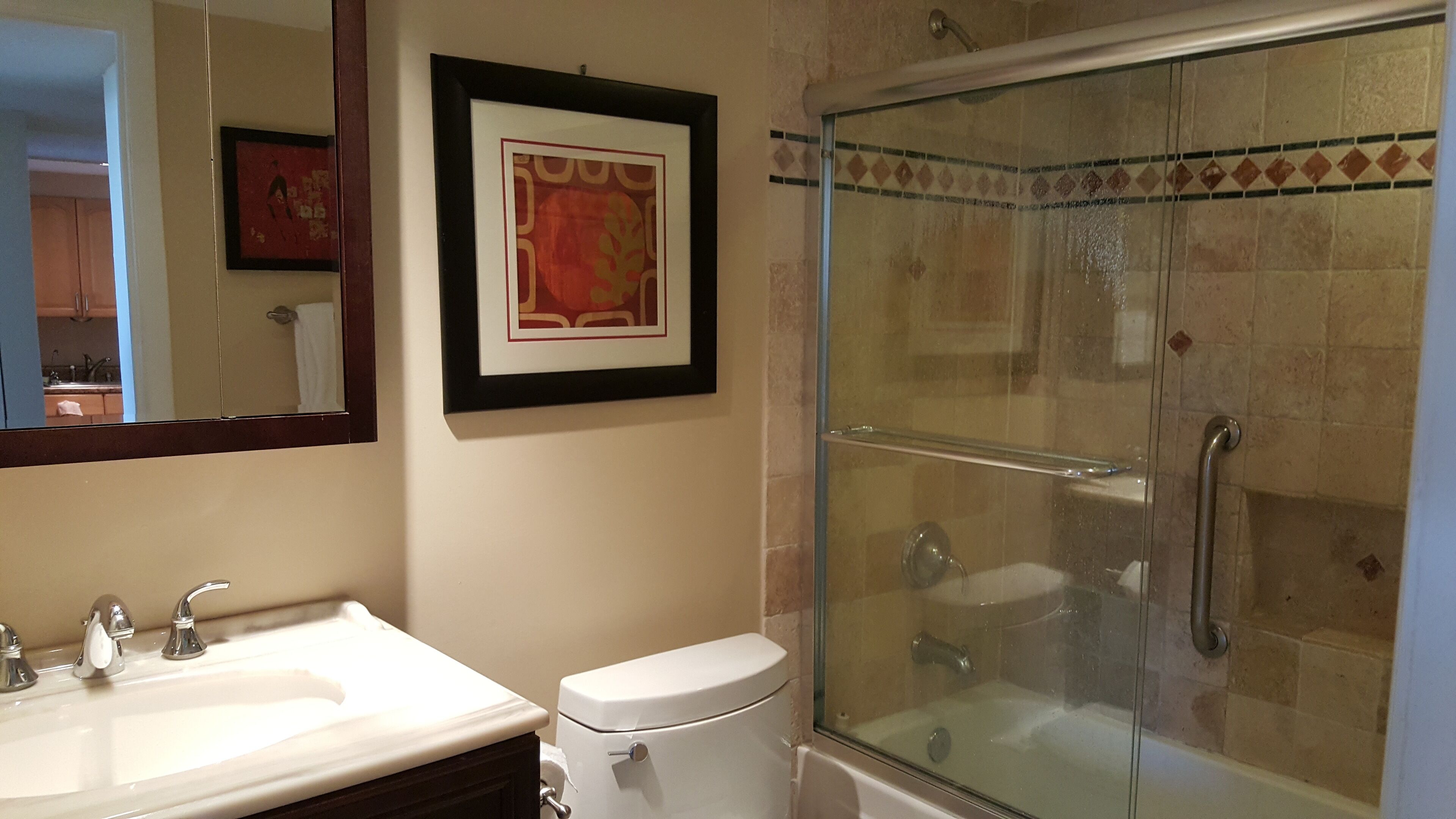 Een badkamer met een wastafel, toilet en douchecabine met glazen wanden.