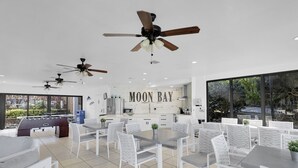 Una cocina moderna con una isla grande, muebles blancos y vistas al exterior.