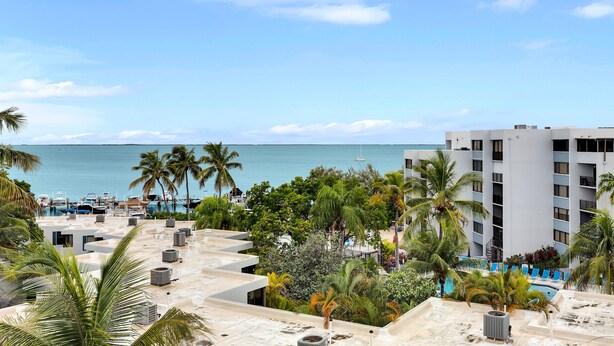 Un resort con piscina, palmeras y vista al océano.