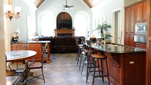 Une cuisine spacieuse dotée d’un îlot central, de tabourets de bar et d’un coin repas avec une table ronde et des chaises.