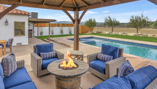 An outdoor patio with wicker furniture, a fire pit, and a pool. - Luxury Adobe in Wine Country w/ Pool, Hot Tub & Ping-Pong, 10 min from downtown (Paso Robles)