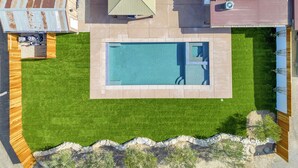 A rectangular swimming pool with a stone border, surrounded by a well-maintained lawn. - Luxury Adobe in Wine Country w/ Pool, Hot Tub & Ping-Pong, 10 min from downtown (Paso Robles)