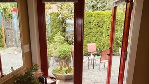 A room with a wooden floor, a patterned rug, a potted plant, and a view of a garden through a glass door. - Serene getaway close to the beach with garden for couples or solo adventurers  (Port Hadlock-Irondale)
