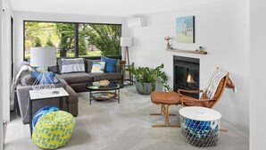 A modern living room with a sofa, armchair, coffee table, and a fireplace. - River's Edge (Leland)