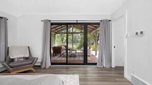 A modern bedroom with a large sliding glass door leading to an outdoor patio. - River's Edge (Leland)