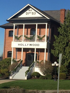 A two-story brick building with a balcony and a sign reading '1912 DIST 83 HOLLYWOOD.' - Wine Country Hollywood Hill Home In Woodinville (Woodinville)