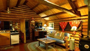 Acogedor interior de cabaña de madera con cocina, comedor y sala de estar.