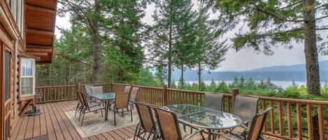 A wooden deck with outdoor furniture, overlooking a lake and forested area.