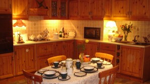 A cozy kitchen with wooden cabinets, a dining table set with plates, cups, and a lace tablecloth.