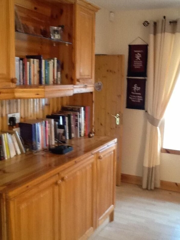 Una estantería de madera con libros, una puerta y una cortina.