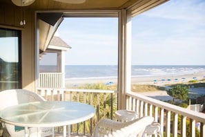 Enjoy the ocean view from this balcony with a glass table and wicker chairs.