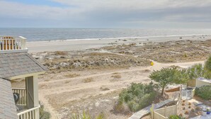 Blick auf einen Strand mit einem Gebäude, das einen Balkon mit Meerblick hat.