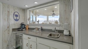 Eine Küche mit Holzwand, einem Spülbecken, einem Fenster mit Aussicht und einem Deckenventilator.