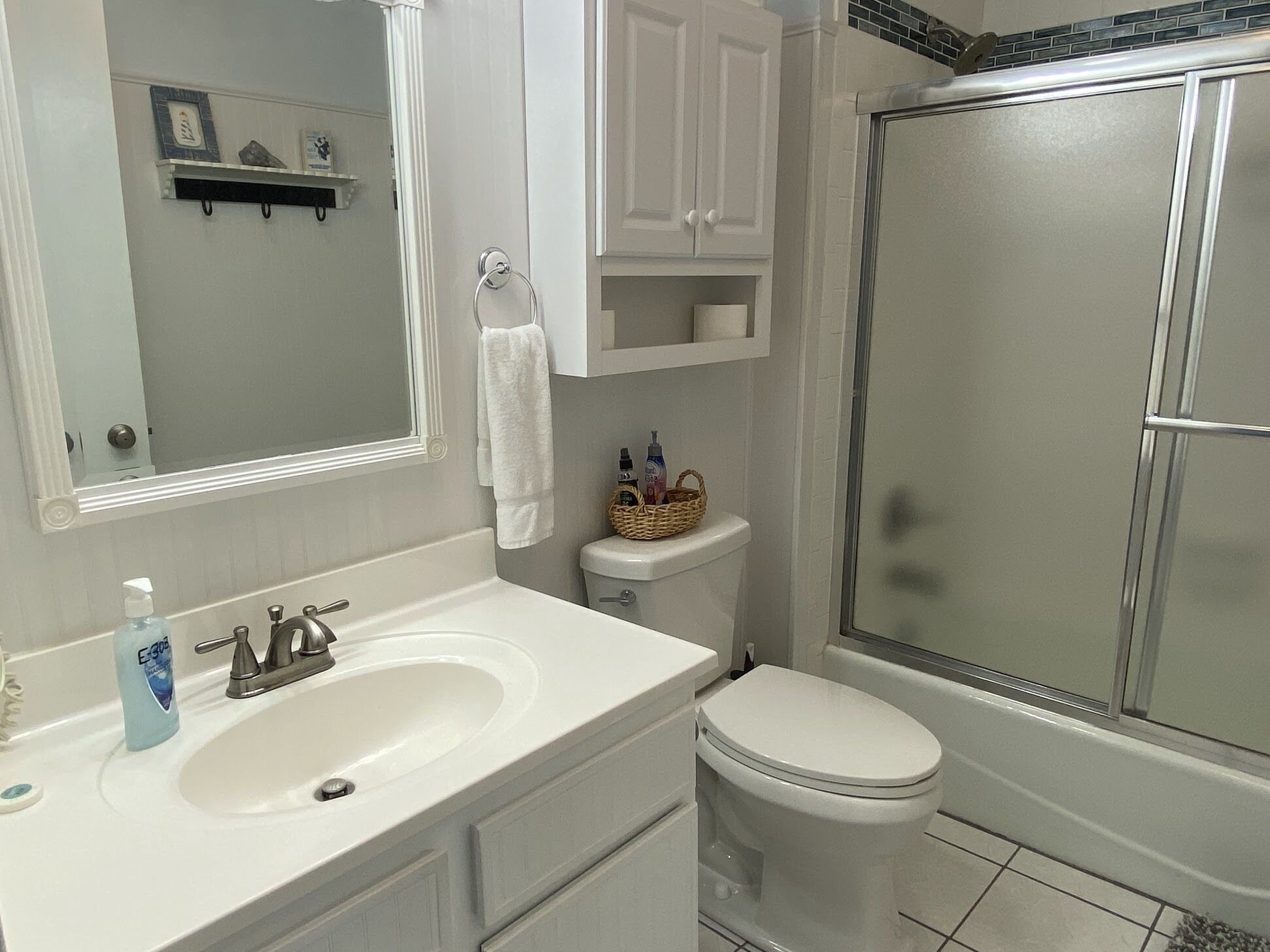 A bathroom with a white sink, a mirror, a toilet, and a glass shower enclosure.