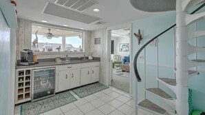 Eine Küche mit integriertem Weinkühler, Deckenventilator und Blick zum Wohnbereich.
