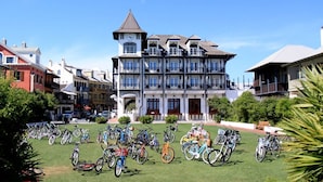 A large building with multiple balconies and a clock tower, surrounded by bicycles.