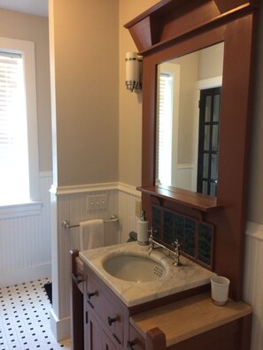 Une salle de bain avec un lavabo en marbre, un meuble-lavabo en bois et un miroir.