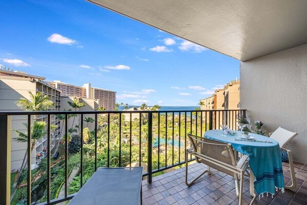 Ein Balkon mit Tisch und Stühlen mit Blick auf einen Pool und Grünflächen.