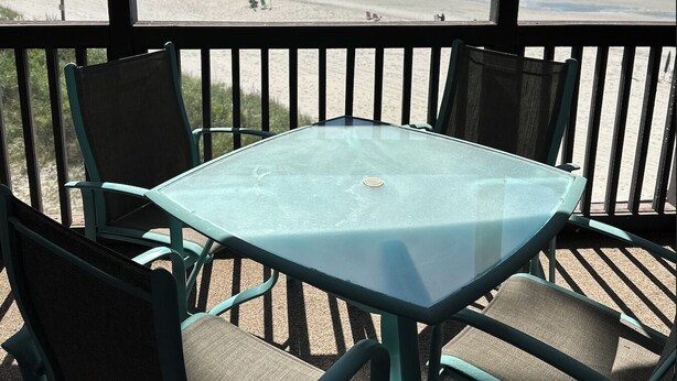 Varanda com mesa e cadeiras com vista para a praia.