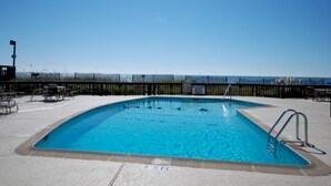Piscina retangular com uma escada de metal em um dos lados, rodeada por um deck de concreto.