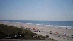 Uma praia com guarda-sóis e pessoas.
