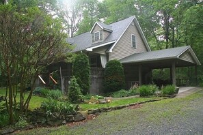 A two-story house with a covered porch, surrounded by a landscaped garden with various plants and a stone pathway. - 8 acres of privacy , stream and waterfall, Dupont, pets welcome. (Cedar Mountain)