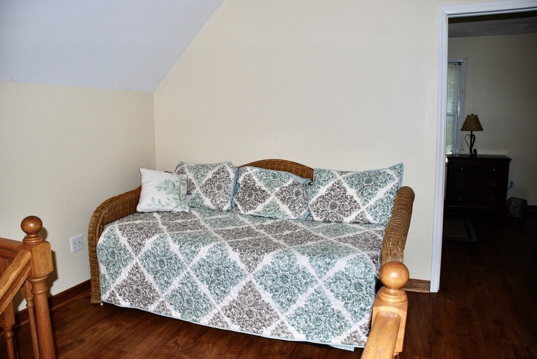 A bedroom with a bed, wooden headboard, and a nightstand with a lamp.