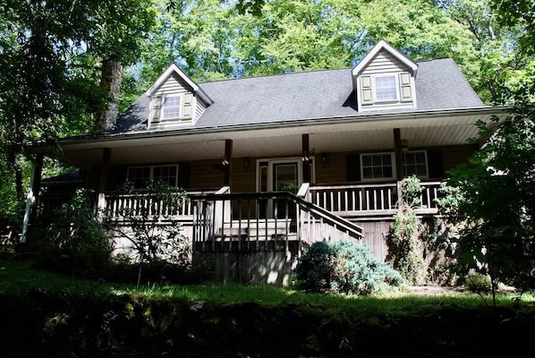 A two-story house with a porch, wooden railings, and a stone foundation. - 8 acres of privacy , stream and waterfall, Dupont, pets welcome. (Cedar Mountain)