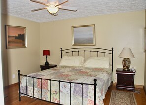A bedroom with a bed, a nightstand, a lamp, a ceiling fan, and two framed pictures on the wall. - 8 acres of privacy , stream and waterfall, Dupont, pets welcome. (Cedar Mountain)