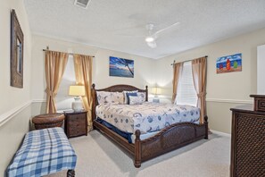 A bedroom with a wooden bed, two bedside tables, a nightstand, a bench, and a ceiling fan. - Beachfront  Panoramic Views,  Covered Patio, Clean, 6 Miles from Town (galveston)