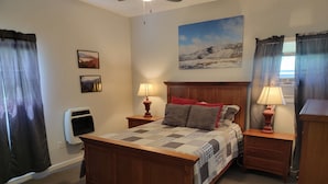 A bedroom with a wooden bed, two bedside tables with lamps, a ceiling fan, and a large landscape painting on the wall. - RIVERFRONT Cabin on Nantahala River, Minutes from NOC (Nantahala)