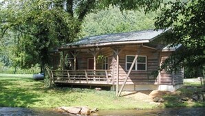 A rustic cabin with a wooden deck, a small porch, and a stream in front. - RIVERFRONT Cabin on Nantahala River, Minutes from NOC (Nantahala)