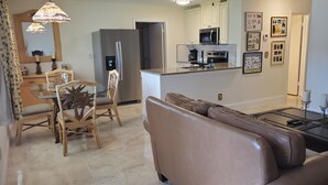 Una cocina moderna con electrodomésticos de acero inoxidable, un comedor con sillas de mimbre y una sala de estar con un sofá de cuero.