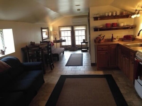 A compact kitchen with a dining area, a sofa, and a window.