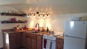 Una cocina con armarios de madera, una estufa blanca, un lavamanos y un refrigerador.