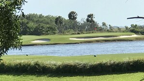 Golfkenttä, jossa on vesialue, hiekkabunkkereita ja taustalla puita.