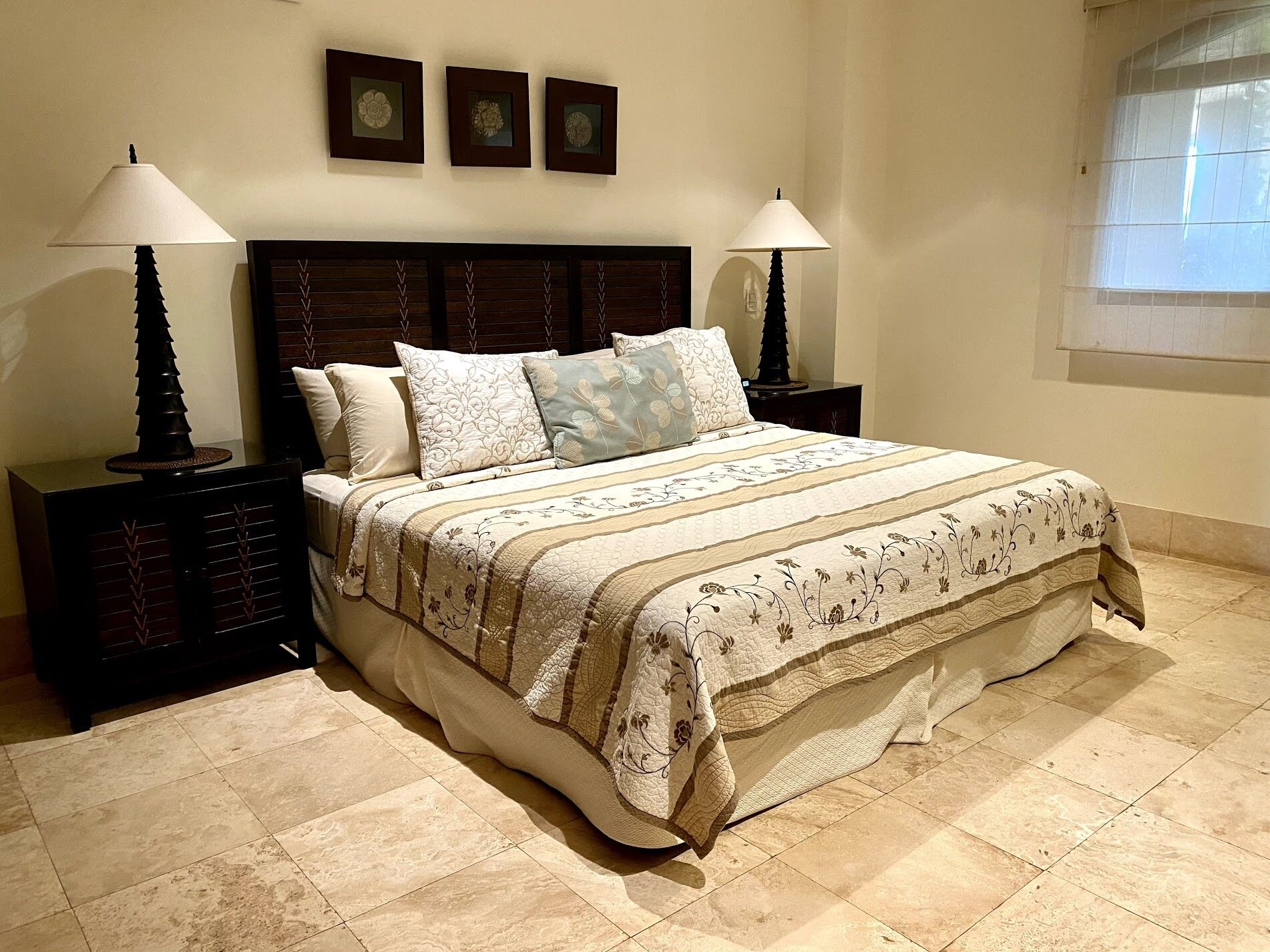 A neatly made bed with a floral-patterned bedspread and pillows, flanked by two nightstands with lamps.