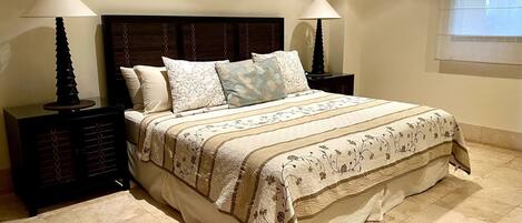 A neatly made bed with a floral-patterned bedspread and pillows, flanked by two nightstands with lamps.