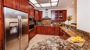A kitchen with wooden cabinets, a stainless steel refrigerator, granite countertops, and a built-in oven.