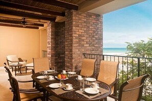 Un comedor con pared de ladrillo, una mesa lista para cuatro personas y vista al océano.