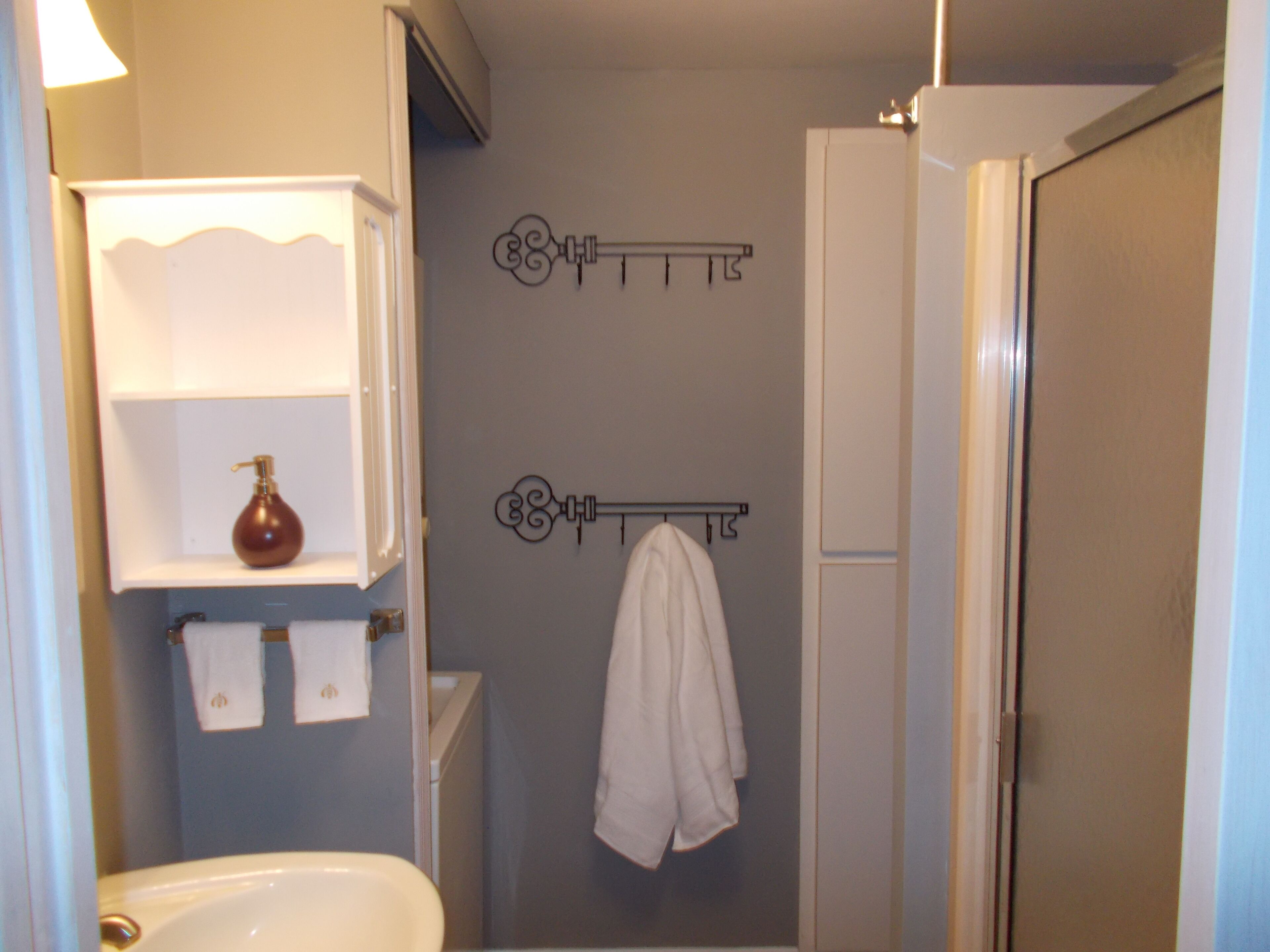 Een badkamer met een witte badkuip, een handdoekrek met een witte handdoek en een zeepdispenser op een plank.