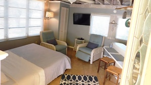 Una habitación acogedora con una cama, dos sillones, una mesita y un televisor.