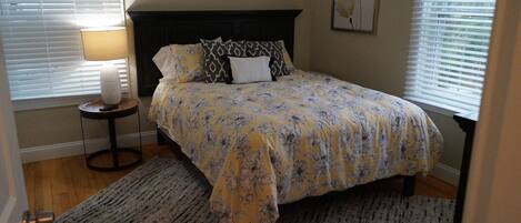 A bedroom with a bed, a nightstand, a lamp, and a painting on the wall.