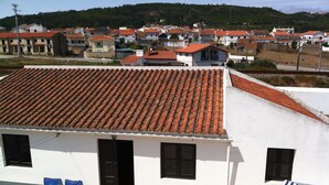 A building with a tiled roof, two blue lounge chairs, and a striped umbrella. - Country and  beach, the best of both worlds. (Famalicão da Nazaré)